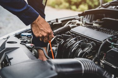 Otomobil tamircisi, motor yağı seviyesini araba motor yağı konseptini değiştirerek bakım ve araba sigortasını kontrol ediyor..