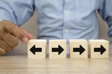 İş adamı eliyle, ok başı simgelerinin iş dünyasının büyüme ve başarı kavramlarının lideri için zıt yönleri gösterdiği tahta bloğu seçti.