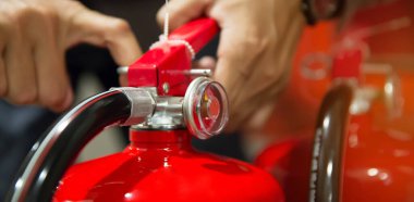 Yangın koruma mühendisi, yangın önleme acil durumu ve itfaiye ve eğitim hizmetlerinin güvenliği için bina konseptindeki kırmızı yangın söndürme tankının pimini kontrol et..