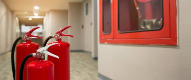 Red fire extinguishers tank at the exit door in the building concepts of emergency safety for fire prevention rescue and fire services concetps. clipart