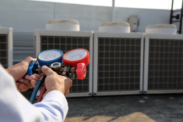 Manifold göstergesi kullanan teknisyen endüstriyel fabrika klimalarını doldurmak ve dış hava kompresör ünitesini kontrol etmek için ekipman ölçüyor..