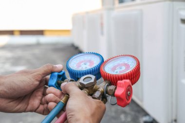 Manifold göstergesi kullanan teknisyen endüstriyel fabrika klimalarını doldurmak ve açık hava kompresör ünitesini kontrol etmek için ekipman ölçüyor..