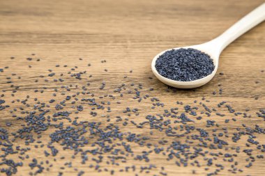Sağlıklı yemek ve diyet kavramları için tahta kaşıkta siyah susam tohumları..