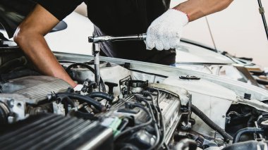Otomobil tamircisinin yakın çekim elleri araba garajındaki bir araba motorunu tamir etmek için ingiliz anahtarını kullanıyor. Araba bakımı, tamirat ve hizmet kavramları.