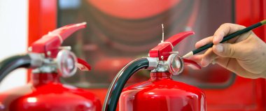 İtfaiyeci, yangın önleme ve itfaiye eğitimlerinin güvenliği alanındaki yangın söndürme tankının basınç göstergesini kontrol ediyor..