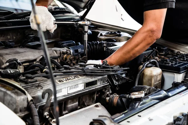 Close-up hands of auto mechanic are using the wrench to repair a car engine in auto car garage. Concepts of car care fixed repair and services.