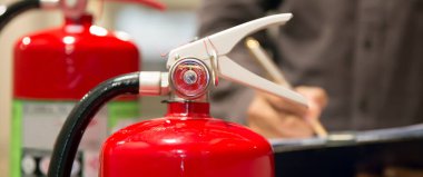 Fire fighter are checking pressure gauge of red fire extinguishers tank in the building concepts of fire prevention and safety of fire services training. clipart