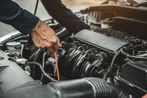 Otomobil tamircisi, motor yağı seviyesini araba motor yağı konseptini değiştirerek bakım ve araba sigortasını kontrol ediyor..