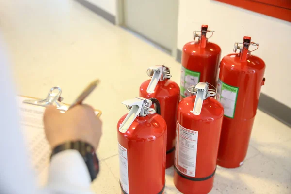 消防士は 火災予防の緊急性と火災サービスと訓練の安全救助の建物の概念で赤い消火器タンクをチェックしています — ストック写真
