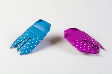 İki origami Beatles, mor ve mavi kağıtlardan yapılmış, beyaz noktalı, beyaz arkaplanda izole edilmiş.