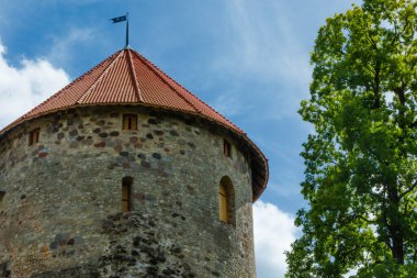 Letonya, Cesis 'te kırmızı çatılı ortaçağ taşlı kalesi. Eski Avrupa mimarisi. Kule ve yeşil ağaç.