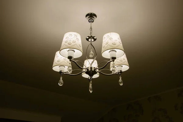 Modern chandelier in classic design on the ceiling. Interior of apartment. Lighting lamp.