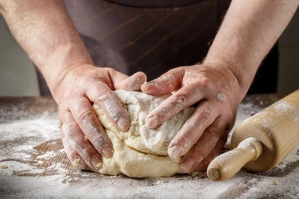 Erkek elleri hamur işini ekmek ya da diğer hamur işleri için ahşap bir masa üzerinde un ile hazırlıyor.