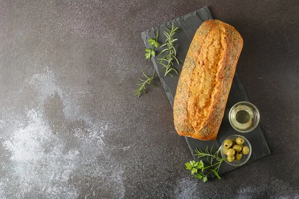 Taze pişmiş İtalyan Ciabatta 'sı. Taş tahtada otlar, baharatlar ve zeytinlerle birlikte. Kopyalama alanı olan üst görünüm