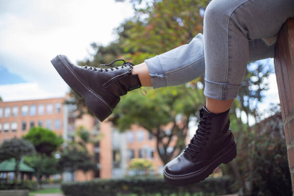 кожаные сапоги с голубыми джинсами, на улице на заднем плане, сидя, на открытом воздухе, образ жизни