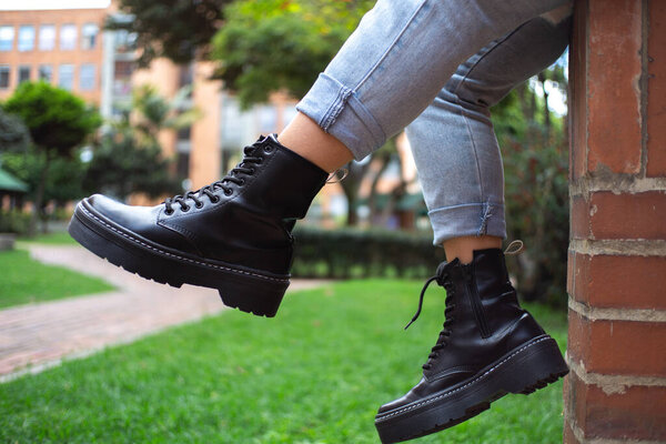 кожаные сапоги с голубыми джинсами, на улице на заднем плане, сидя, на открытом воздухе, образ жизни