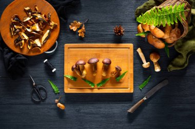 Forest mushroom on the cutting board on a black table.