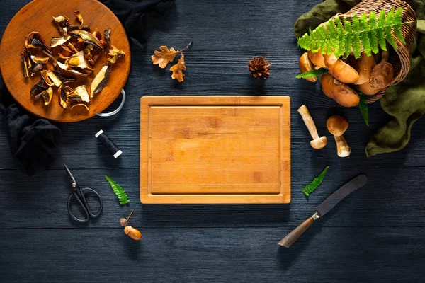 Mushroom Boletus and cutting board on black table. Copy space Rechtenvrije Stockafbeeldingen