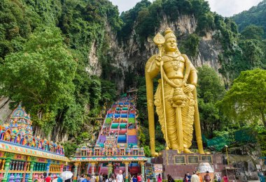 Kuala Lumpur,Malaysia - December 12 , 2018: Batu Caves is a limestone hill that has a huge statue of The Lord Murugan Giant located at the entrance of Batu Caves. People can seen exploring around it. clipart