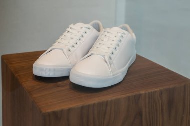 Ahşap ekran standındaki beyaz ayakkabıların yakın çekim.