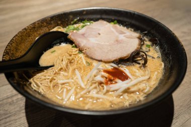 Yavaş pişmiş Charsiu, yeşil soğan, mantar ve lahanayla kaplı Japon eriştesinin yakın çekim görüntüsü..