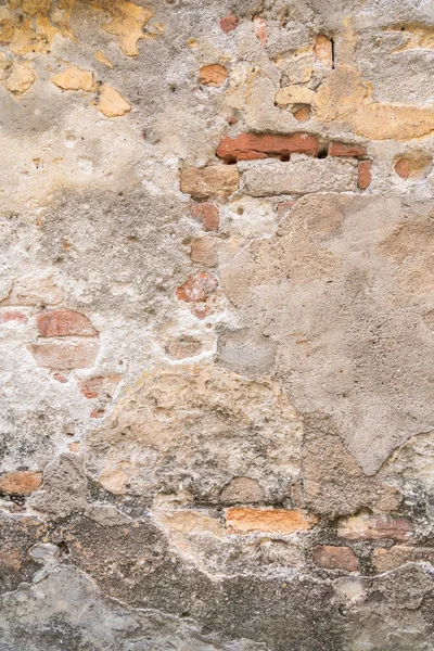 Açıkta duran tuğlaları ve sıcak tonlarda yıpranmış dokuları olan eski bir köy duvarı.