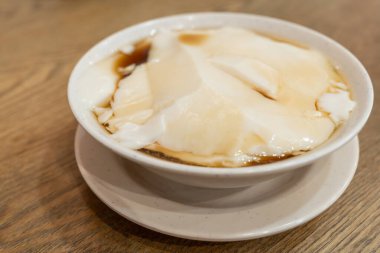 Bir kase geleneksel Çin usulü tofu pudingi, tau foo fah ya da douhua olarak da bilinir, tatlı şurupla servis edilir. Tahta masadaki beyaz kasede yumuşak soya peynirli tatlı..