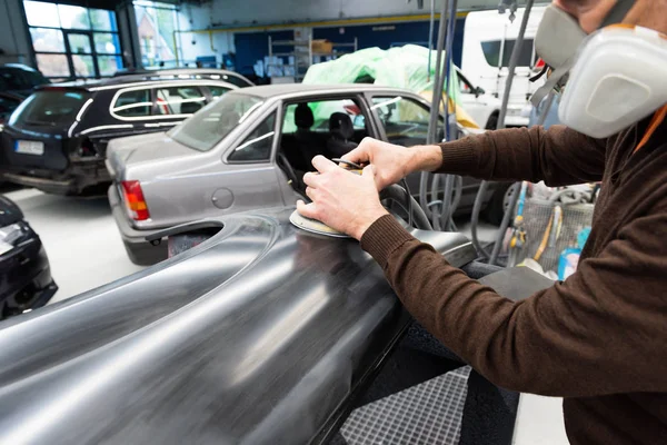 Mécanicien automobile meule une pièce de voiture dans une station-service - Serie atelier de réparation automobile Images De Stock Libres De Droits