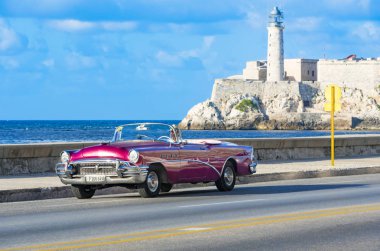 Havana, Küba - Ekim 04, 2018: Amerikan kırmızısı 1955 Buick üstü açık klasik arabası Malecon gezinti güvertesinde ve arka planda Havana City Cub 'daki Castillo de los Tres Reyes del Morro
