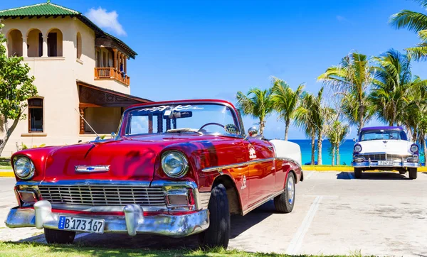 Havana, Küba - 28 Eylül 2018: Amerikan kırmızı Chevrolet üstü açık klasik arabası Havana Küba 'da arka planda Ford Fairlane ile plaja park edilmiş