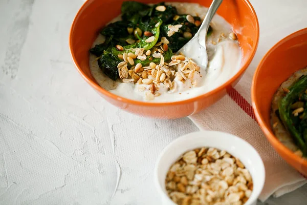 Healthy savory oatmeal with greens and Bulgarian yogurt high in fiber and protein in bowl on gray background,easy to prepare for breakfast or brunch.Healhty food,balanced diet concept
