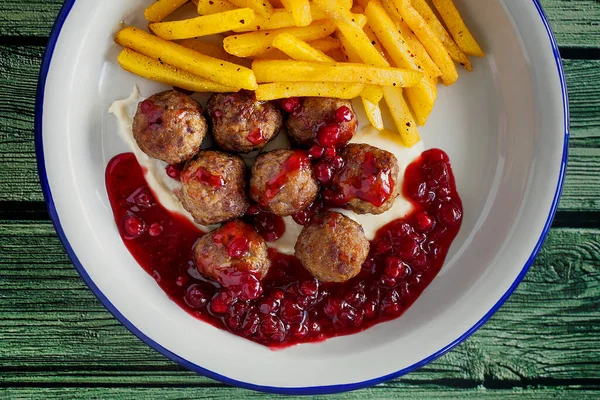 Swedish meatballs with french fries side dish and lingonberry sauce top view close-up