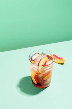 Yeşil kağıttan arka plan manzaralı kekik kaplı soğuk şeftali çayı. Alkolsüz yaz içkisi konseptini tazeliyorum.