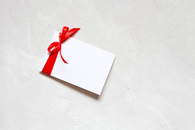 Beyaz kağıt kart tebrik kartı şablonu kırmızı kurdele ile beyaz desenli arka plan. Düz konum, üst görünüm, kopyalama alanı
