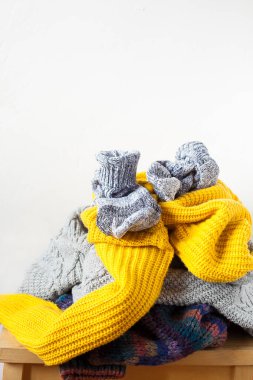 Ahşap masaya örülmüş renkli yün ya da süveter yığınları ve kopya alanla yakın plan beyaz duvar. Akraba bağışı ve ev konsepti.