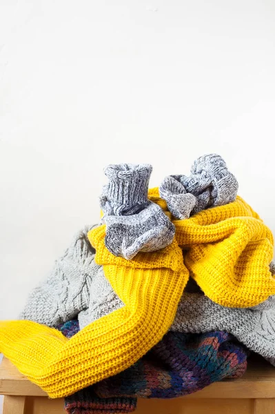 Ahşap masaya örülmüş renkli yün ya da süveter yığınları ve kopya alanla yakın plan beyaz duvar. Akraba bağışı ve ev konsepti.