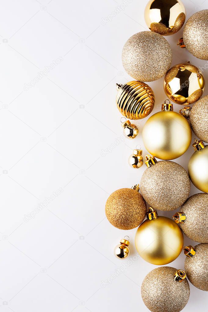 Creative layout made of Christmas golden metallic bauble or balls decoration on white background with copy space.New Year greeting card.Flat lay, top view.Vertical orientation