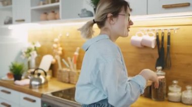 Günlük giysiler içinde zarif genç bir kadın depolamak için mutfak dolabında bir şey arıyor. Her çekmeceye bakıyorum. Kahvaltı ve öğle yemeği için doğru ürünü bulmaya çalışıyorum.