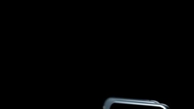Siyah arka planda iki şık akıllı telefon geliyor, dönüyor. Kamera ile donatılmış yeni mobil aygıtların sunumu ve soyut hareketli neon dalgaların görüntüsü ile dokunmatik ekran görüntüsü, 3D görüntüleme