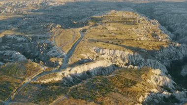 Türkiye 'nin olağanüstü güzel Kapadokya dağları vadisi, gün batımında insansız hava araçları ve kayalık kumtaşı oluşumları, Türkiye' nin popüler turizm beldesi ve manzarası.