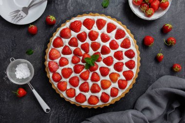 Krem şanti ve mascarpone ile koyu beton arka planda lezzetli çilekli tart. Üst görünüm. 