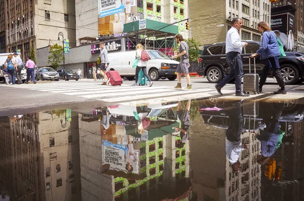 Mensen wandelen door voetgangersoversteekplaats weerspiegeld in een plas. — Stockfoto