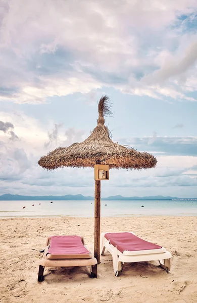 Parasol i dwa leżaki na plaży. — Zdjęcie stockowe