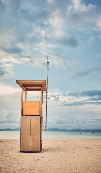Torre de salvavidas en una playa vacía al atardecer . — Foto de Stock