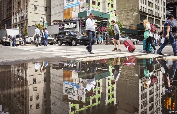 Mensen op voetgangersoversteekplaats weerspiegeld in een plas. — Stockfoto