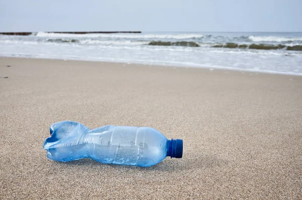 Plastic fles links op een strand. — Stockfoto