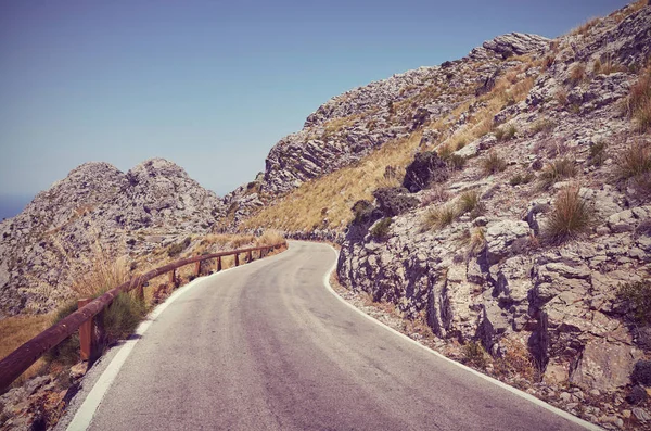 Retro toned picture of a scenic winding mountain road. — Stock Photo, Image