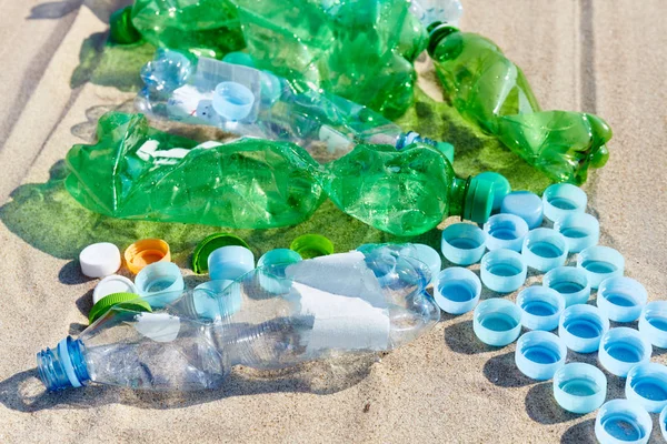 Imagem de perto de garrafas de plástico usadas e bonés em uma praia . — Fotografia de Stock