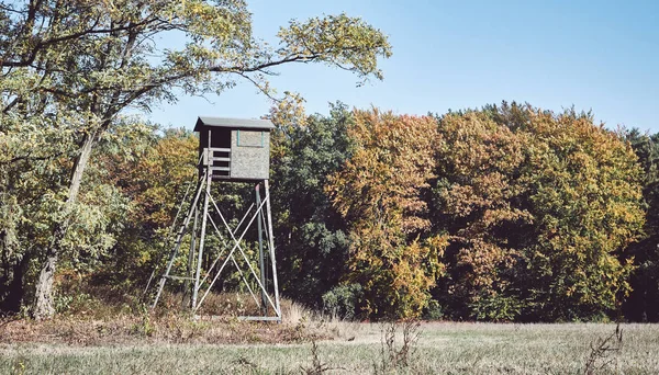 Wooden deer hunting pulpit at the edge of a forest and field. — Stock fotografie