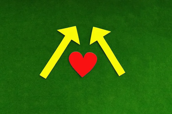 心臓は赤で 黄色の矢印が緑色の背景を指しています — ストック写真
